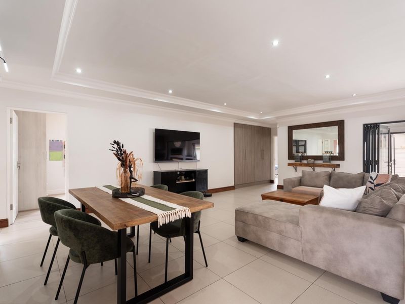 Spacious open-plan living and dining area featuring modern tiled flooring, recessed downlighting, and clean architectural lines throughout the space.