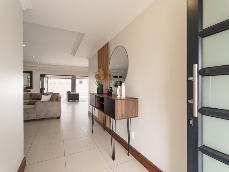 Welcoming entrance hall featuring tiled flooring, a decorative timber slat wall feature, and a modern glass-paneled front door leading into the open-plan living area.