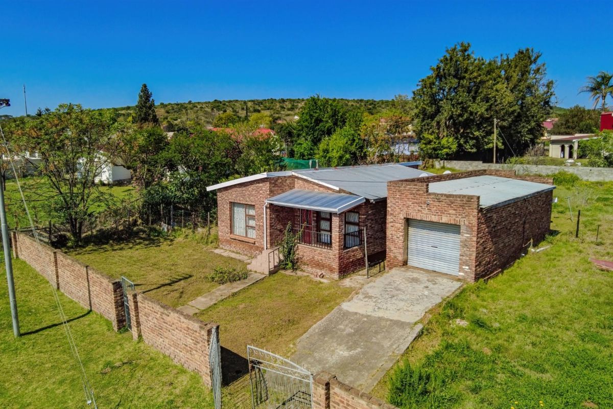 Aerial view of a single-story face brick house featuring a single garage, concrete driveway, and enclosed yard with perimeter walling.