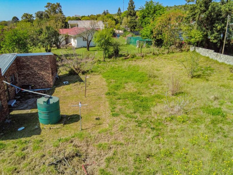 An aerial view of a large, undeveloped garden area featuring a water tank, brick exterior wall, and perimeter boundary walling.