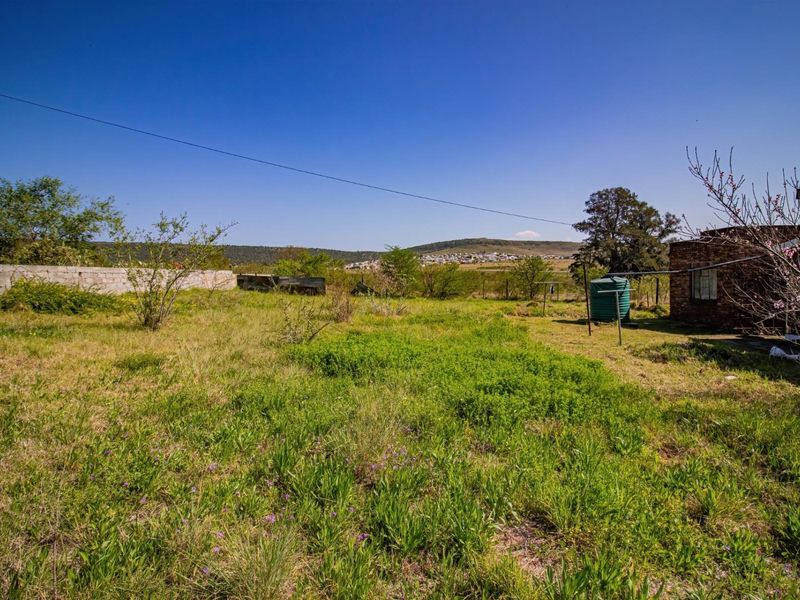 A spacious rear yard featuring a water tank, perimeter walling, and expansive views of the surrounding landscape.