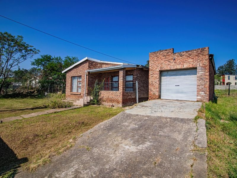 Front view of a face brick house featuring a single garage, concrete driveway, and a covered entrance porch set on a large plot.