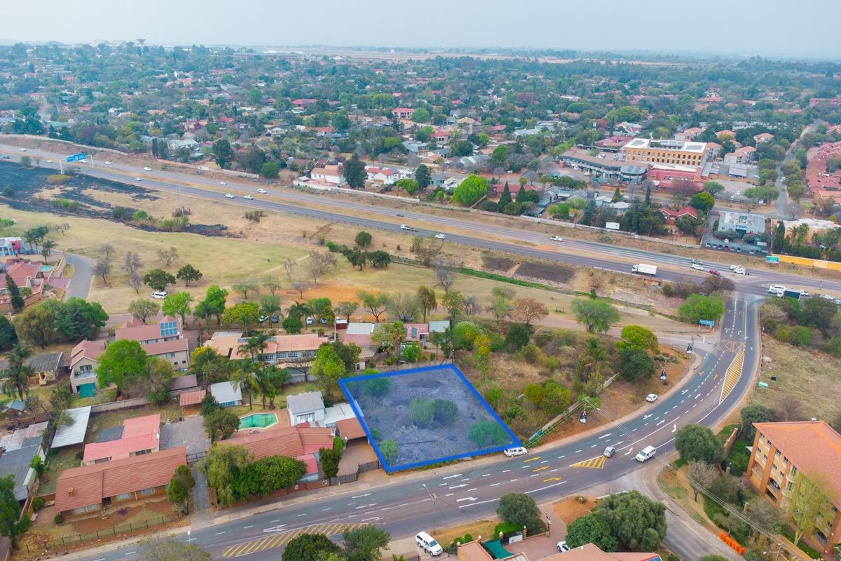 An aerial view of a vacant residential plot, clearly demarcated, situated in a developed suburban area with convenient access to main roads.