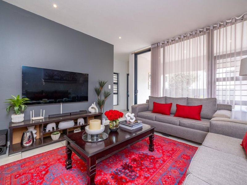 A modern living room featuring a dark accent wall, tiled flooring, and large sliding glass doors that provide ample natural light.