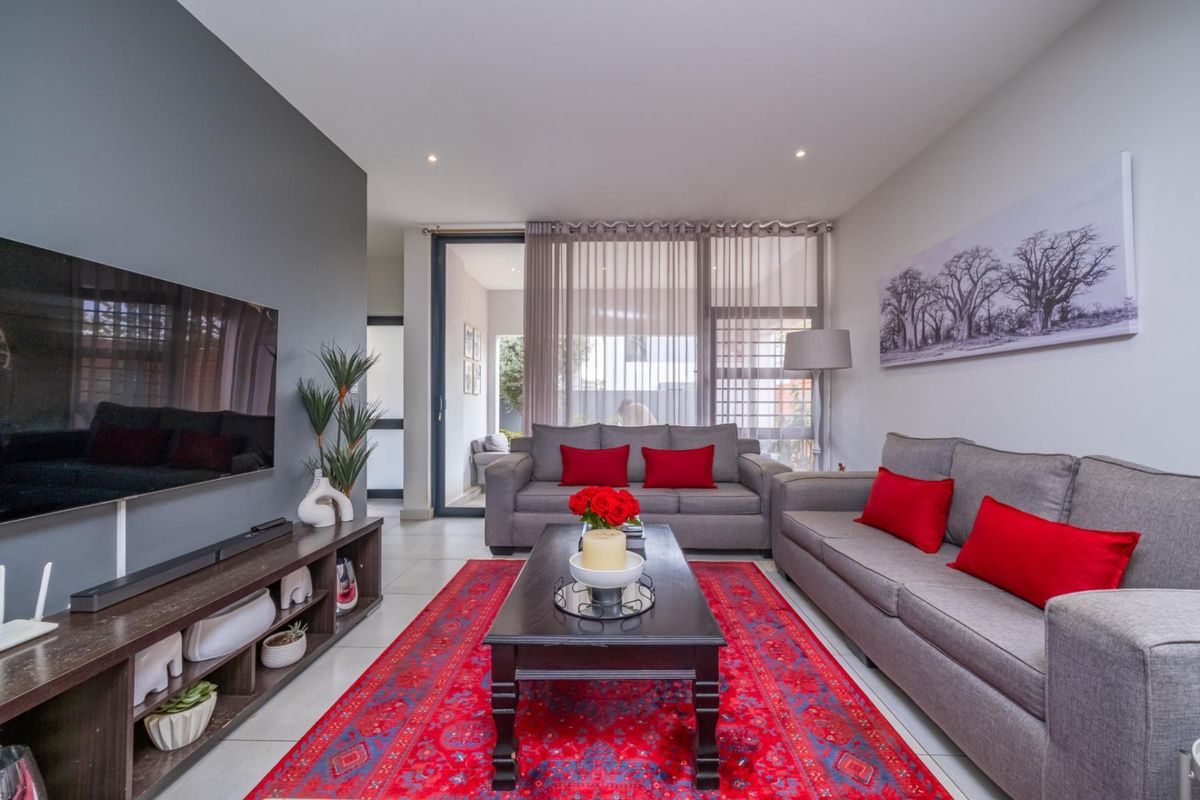 A well-maintained living room featuring tiled flooring, recessed lighting, and a large sliding glass door providing access to the patio area.