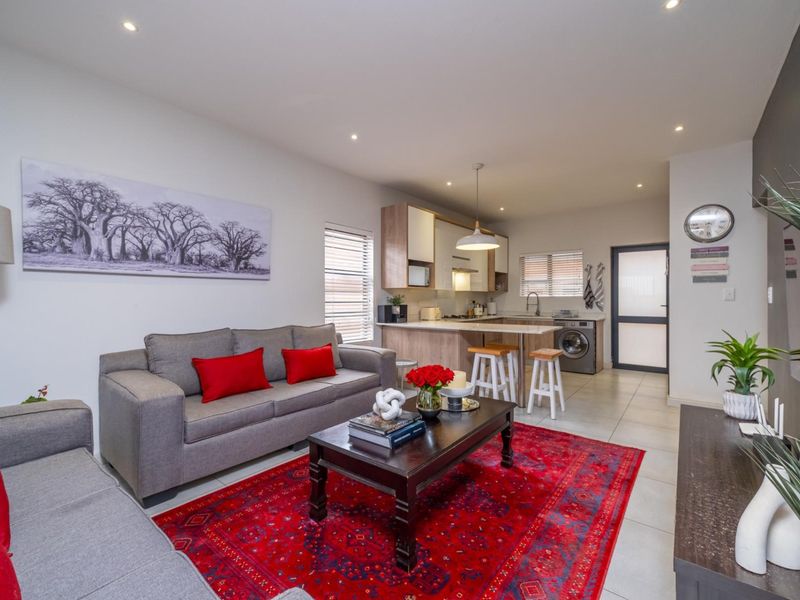 Modern open-plan living area featuring a well-appointed kitchen with stone countertops, integrated appliances, and tiled flooring throughout, creating a seamless and functional living space.