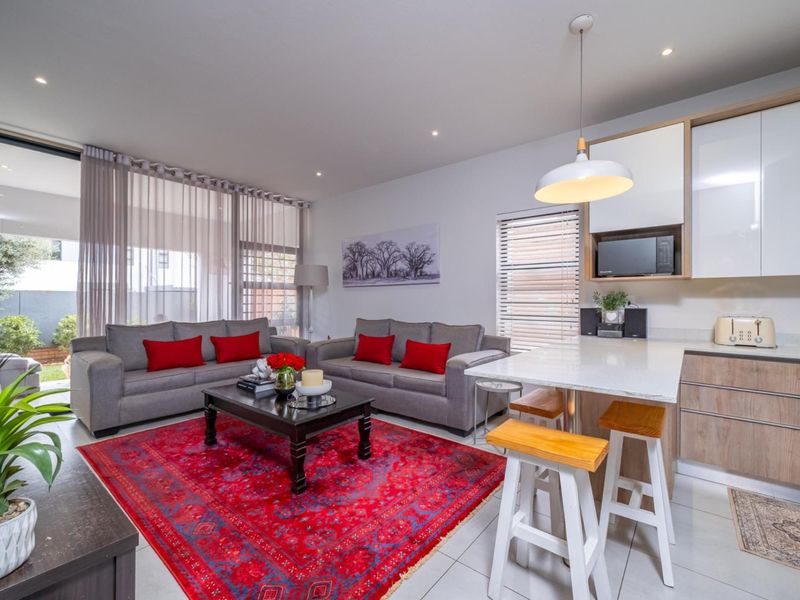 Modern open-plan living area featuring a contemporary kitchen with stone countertops, sleek cabinetry, and seamless flow to an outdoor patio through sliding glass doors.