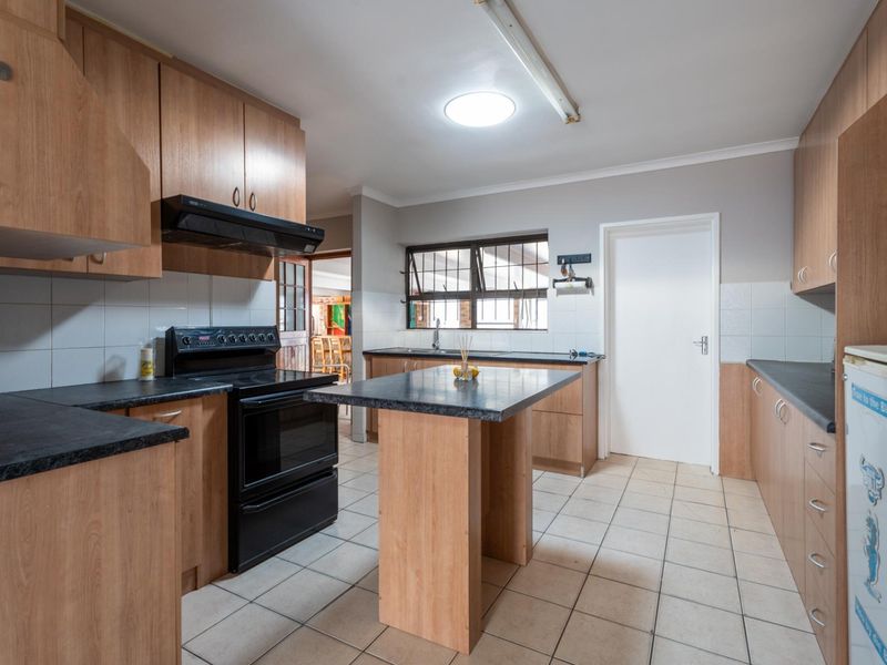 Functional kitchen featuring laminate cabinetry, dark countertops, a freestanding stove with extractor fan, and tiled flooring.