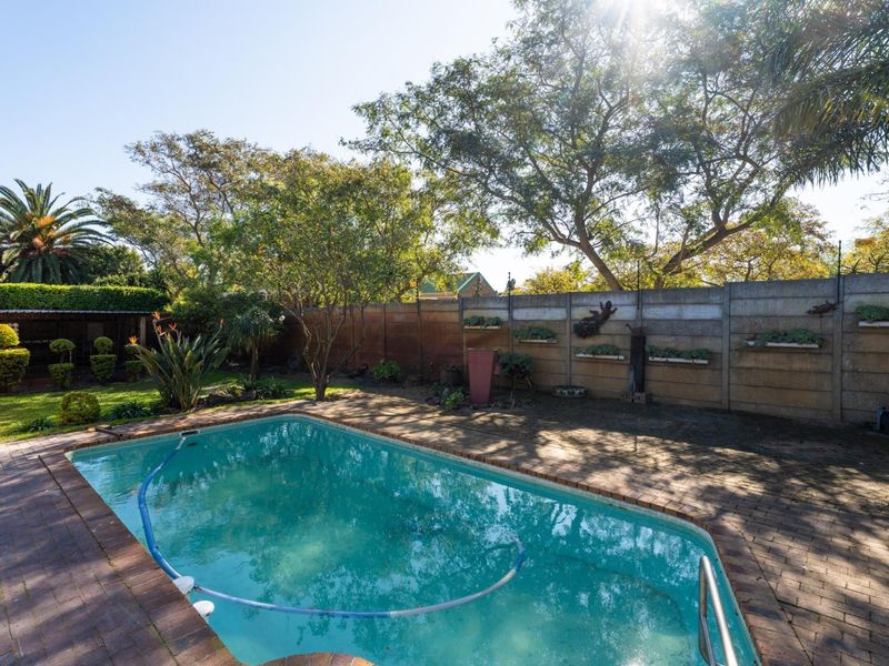 Outdoor pool area featuring a swimming pool, brick paved surround, and a precast concrete boundary wall with integrated planters.