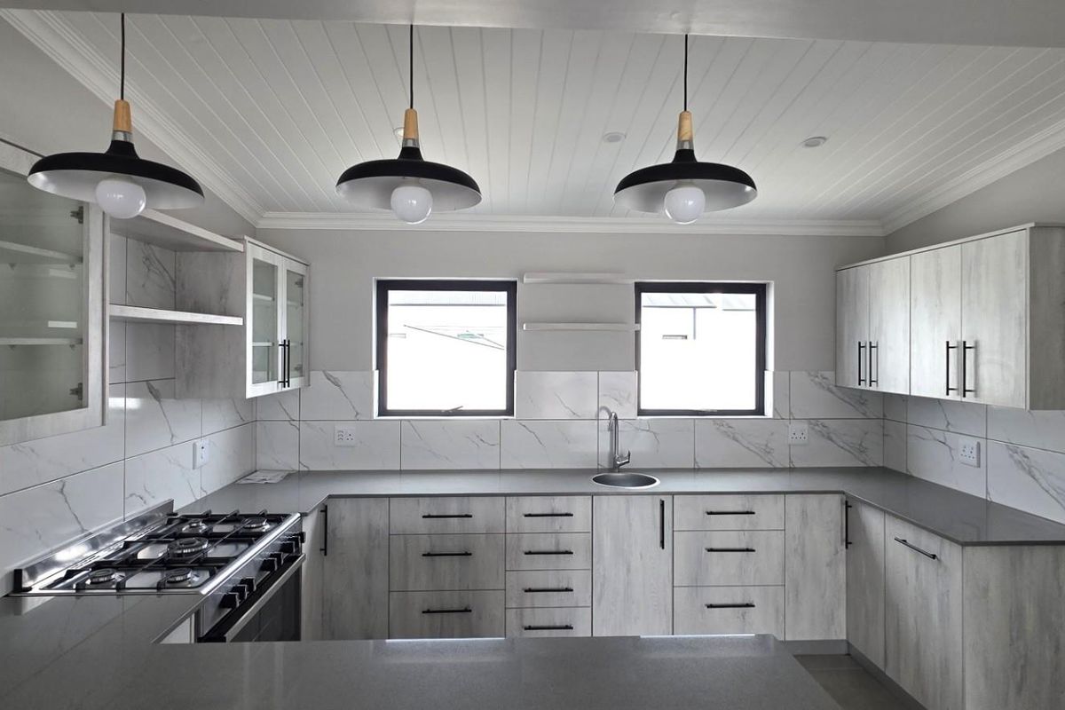 Modern kitchen featuring light wood-grain cabinetry, marble-look tiled backsplash, quartz countertops, gas hob, and stylish pendant lighting in a clean, contemporary layout.