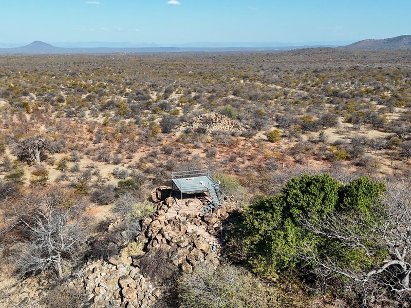 Aerial view of an elevated metal viewing platform situated on a rocky outcrop, overlooking the expansive natural landscape of the farm.