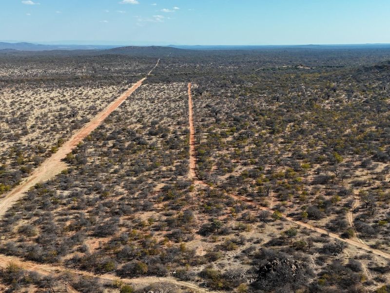 An aerial view of the expansive farm landscape featuring dirt access roads and natural bushveld vegetation.