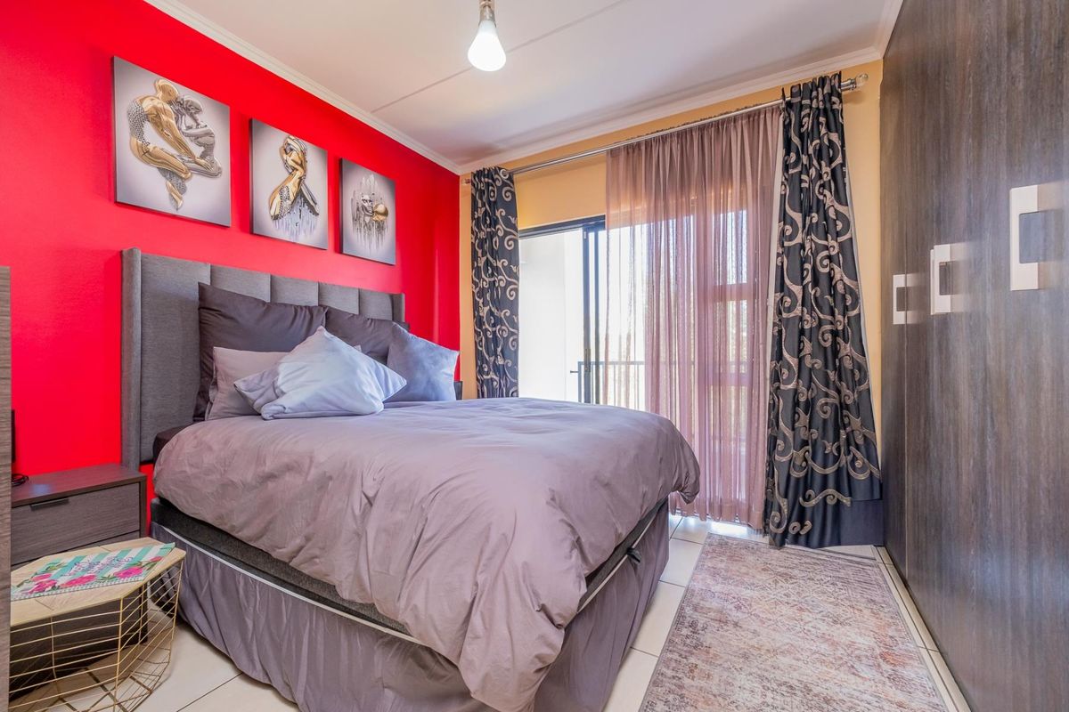 A bedroom featuring built-in cupboards, tiled flooring, and a sliding glass door providing access to an outdoor area.