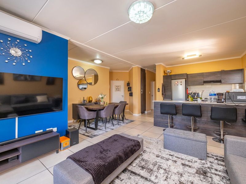 Spacious open-plan living area featuring a modern kitchen with island, tiled flooring, and a split-system air conditioner, seamlessly connecting to the dining and lounge space.