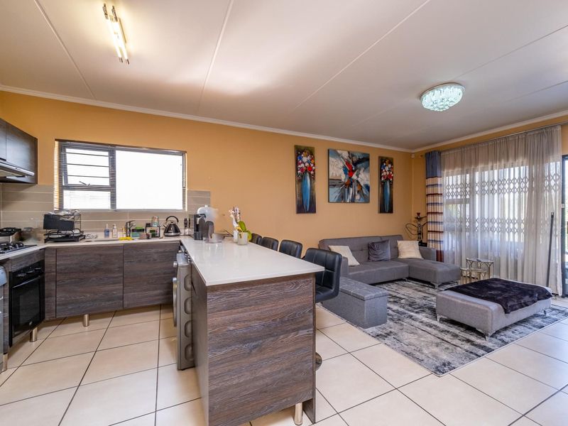 Spacious open-plan living area featuring a modern kitchen with built-in cabinetry, stone countertops, and seamless flow to the lounge and balcony.