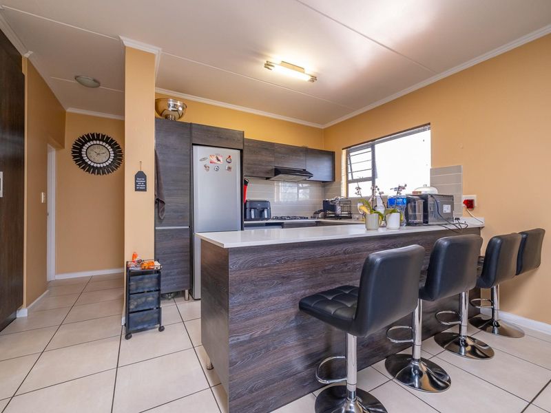 A functional kitchen featuring dark wood-look cabinetry, a breakfast bar with seating, and tiled flooring, offering a practical layout for daily use.