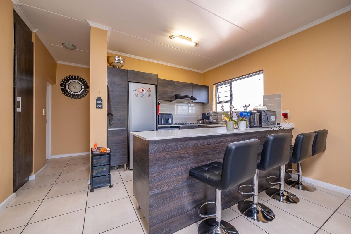 A functional kitchen featuring dark wood-look cabinetry, a breakfast bar with seating, and tiled flooring, offering a practical layout for daily use.