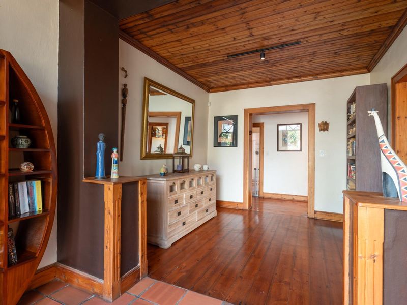 A living area featuring warm hardwood flooring, a distinctive timber-clad ceiling, and classic timber door frames, creating a cozy and traditional atmosphere.