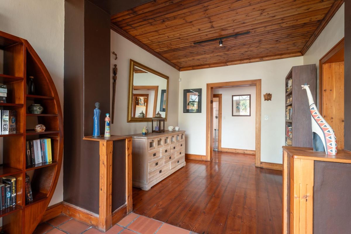 A living area featuring warm hardwood flooring, a distinctive timber-clad ceiling, and classic timber door frames, creating a cozy and traditional atmosphere.