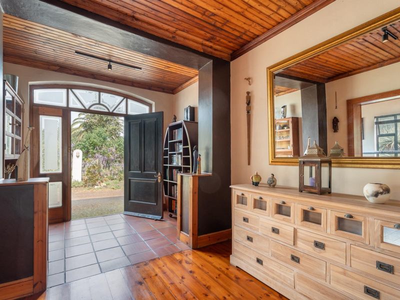 Welcoming entrance hall featuring a combination of terracotta tiling and warm hardwood flooring, complemented by a distinctive timber-clad ceiling and arched glass front door.