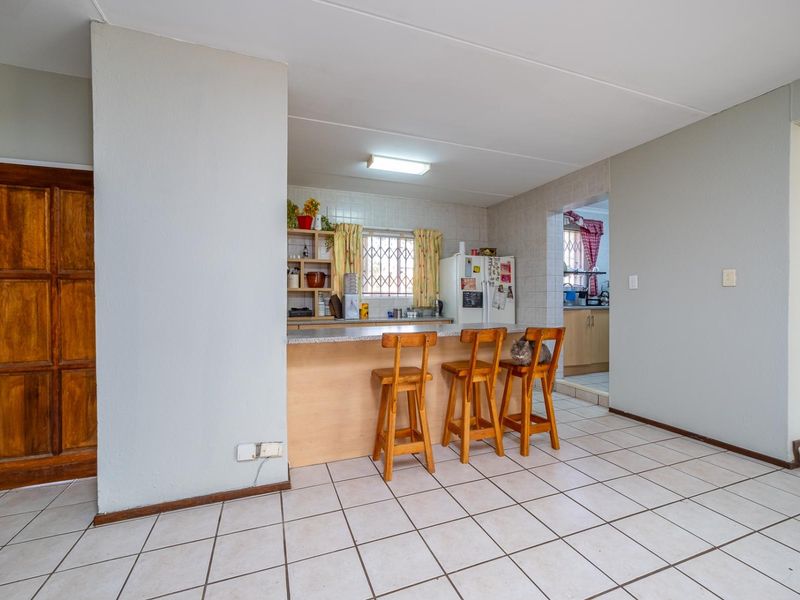 Open plan kitchen and living area featuring tiled flooring, a breakfast bar, and built-in cabinetry with access to a secondary scullery area.