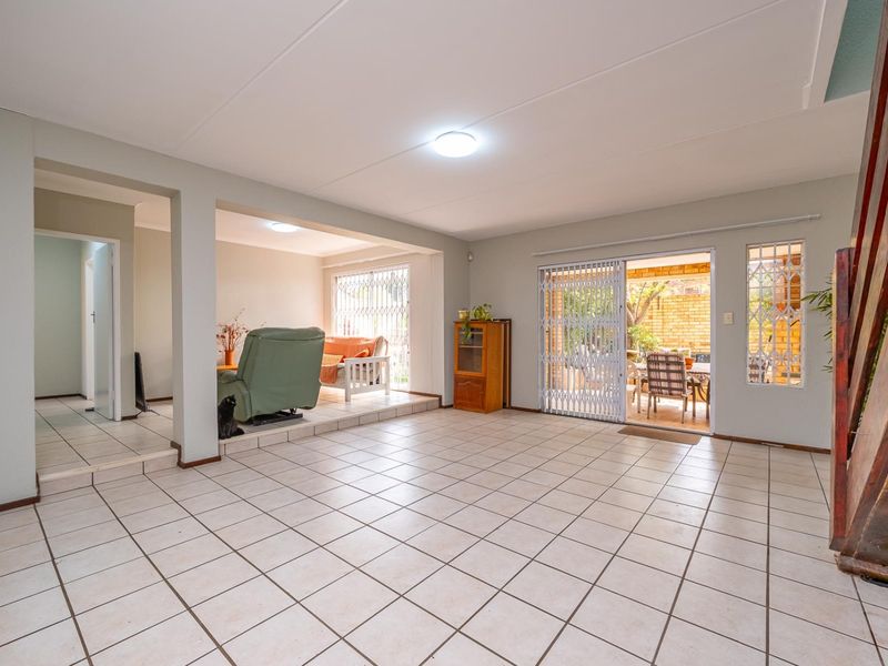 Spacious open-plan living area featuring ceramic tiled flooring, sliding doors leading to the patio, and a staircase to the upper level.