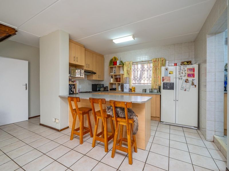 Functional kitchen featuring laminate cabinetry, a breakfast bar, tiled flooring, and a tiled splashback, offering a practical layout for daily meal preparation.