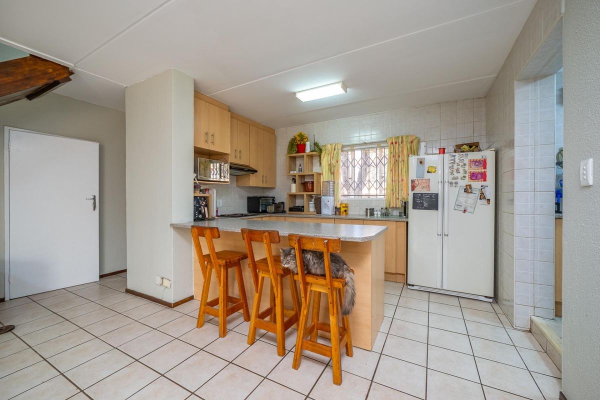 Functional kitchen featuring laminate cabinetry, a breakfast bar, tiled flooring, and a tiled splashback, offering a practical layout for daily meal preparation.