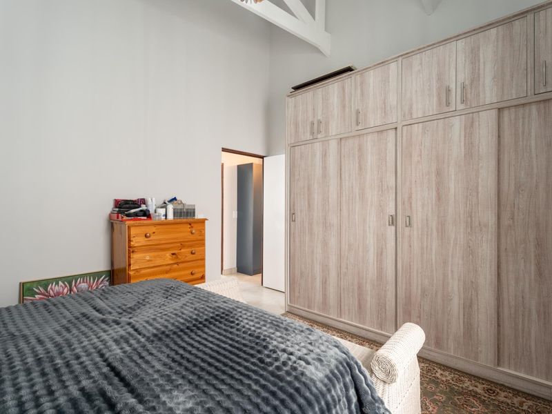Spacious bedroom featuring high vaulted ceilings with exposed trusses and extensive built-in cabinetry for ample storage.