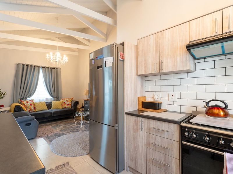 Open-plan living area featuring a modern kitchen with subway tile backsplash, built-in cabinetry, and a vaulted ceiling with exposed beams.