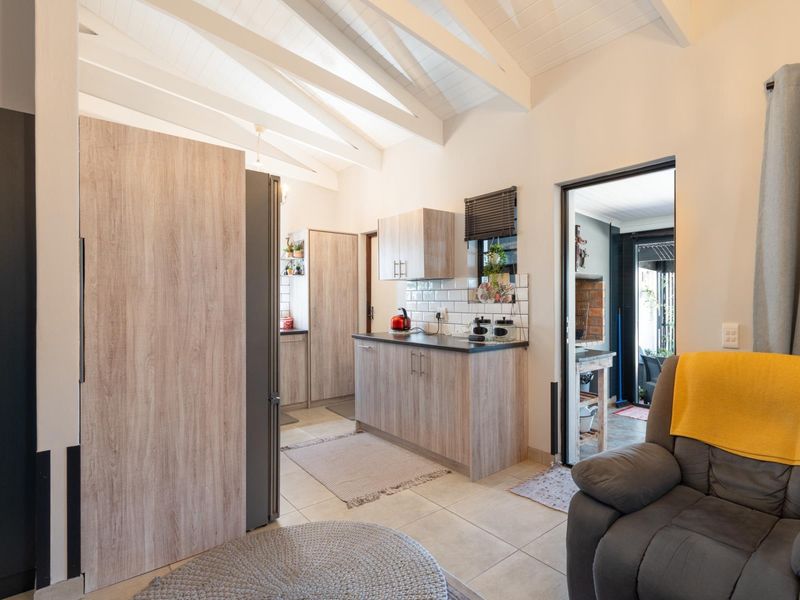 A modern kitchen featuring light wood-grain cabinetry, subway tile backsplash, and a vaulted ceiling with exposed rafters, creating a bright and open atmosphere.