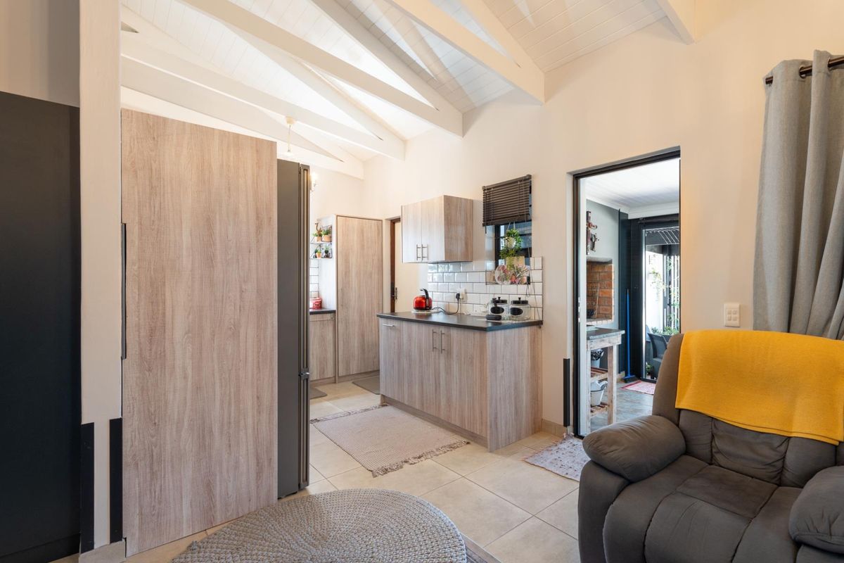 A modern kitchen featuring light wood-grain cabinetry, subway tile backsplash, and a vaulted ceiling with exposed rafters, creating a bright and open atmosphere.