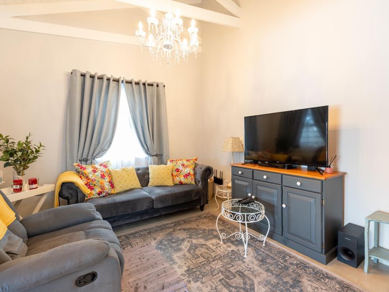 A cozy living room featuring a high vaulted ceiling with exposed beams and a decorative chandelier.