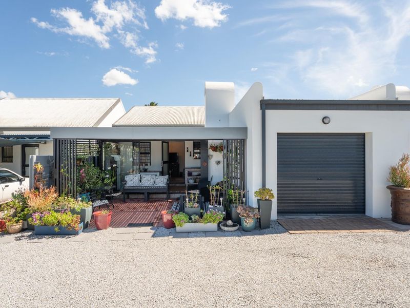 Front elevation of a modern home featuring a single garage, a covered patio area, and a gravel driveway.