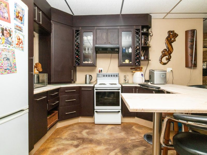 A functional kitchen featuring dark wood cabinetry, a built-in wine rack, a breakfast bar, and a freestanding stove with an extractor fan.