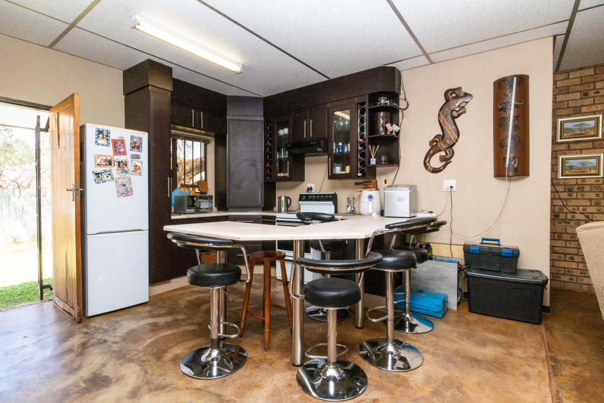 A functional kitchen area featuring dark cabinetry, a central breakfast bar, and exposed brick wall detailing, providing a practical space for meal preparation.