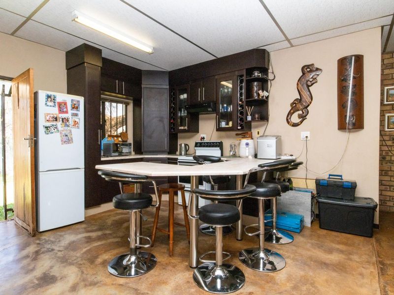 A functional kitchen area featuring dark cabinetry, a central breakfast bar, and exposed brick wall detailing, providing a practical space for meal preparation.