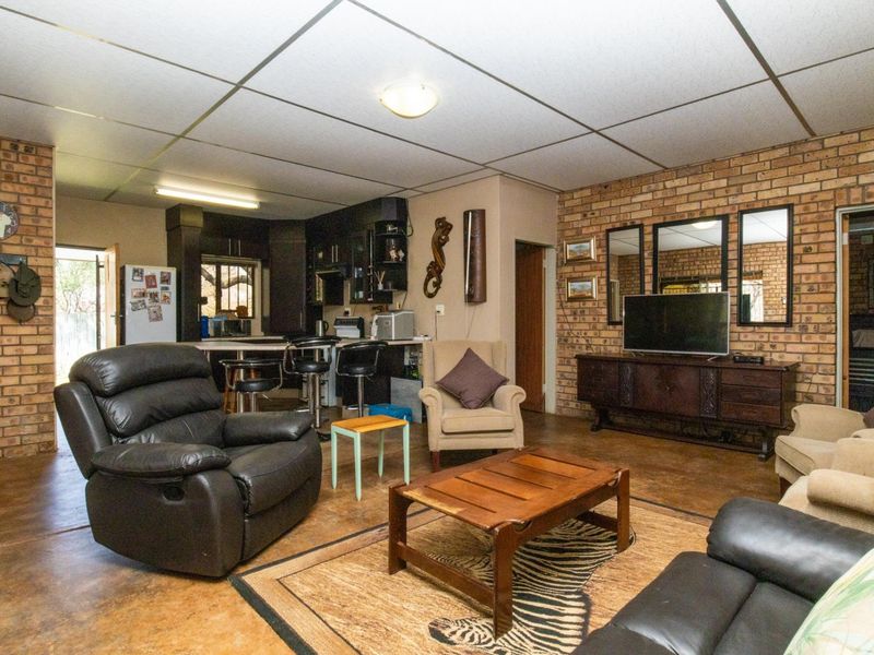 Open plan living and kitchen area featuring exposed brick walls, concrete flooring, and a functional kitchen layout with a breakfast bar.