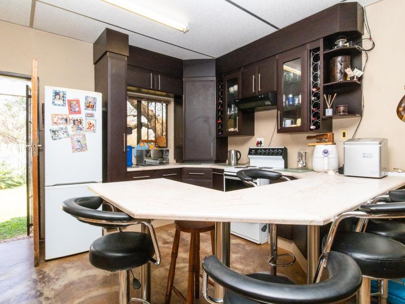 A functional kitchen featuring dark built-in cabinetry, a breakfast bar, and direct access to the garden area.
