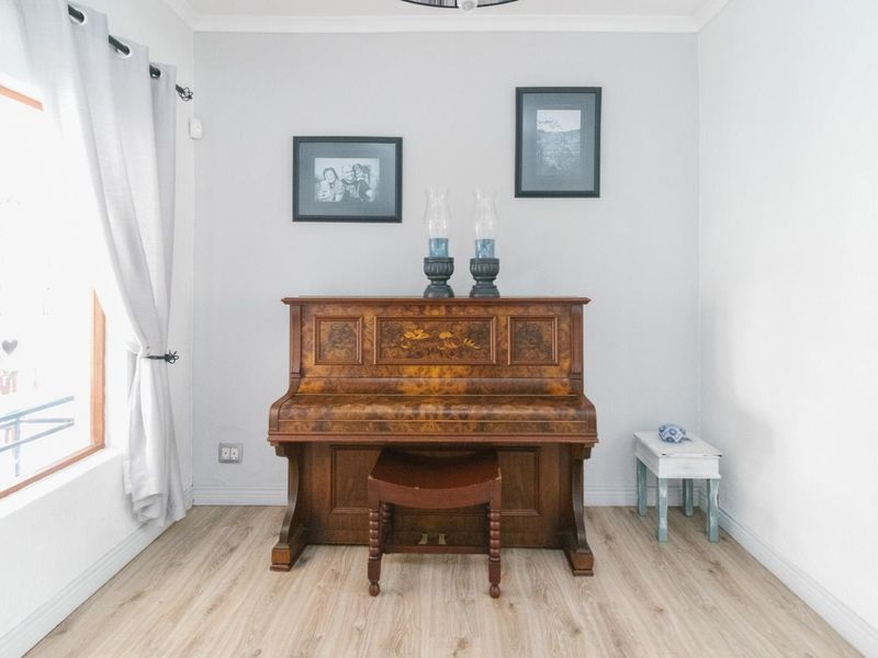 A bright living area featuring light-toned laminate flooring, neutral walls, and coving detail, providing a clean and versatile space.