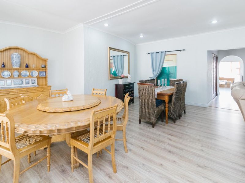 Spacious dining area featuring light-toned laminate flooring, recessed downlighting, and a neutral color palette, providing a bright and functional space for family meals.