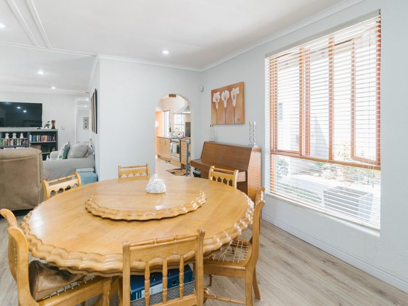 Open plan dining area featuring light laminate flooring, recessed downlighting, and an arched entryway leading to the kitchen.