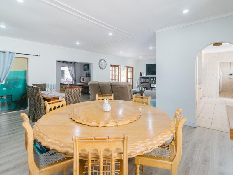 Spacious open-plan living and dining area featuring laminate flooring, recessed lighting, and an arched transition to the adjacent tiled utility space.