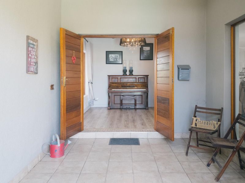 Welcoming entrance area featuring double timber doors, tiled flooring, and a direct view into the adjacent living space.
