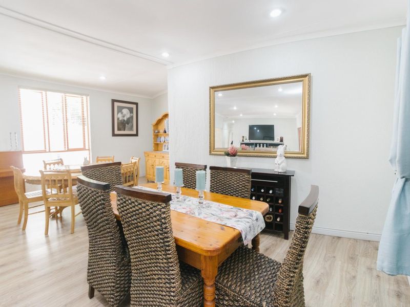 A bright and open dining area featuring modern laminate flooring, recessed downlighting, and neutral wall finishes, providing a comfortable space for family meals.