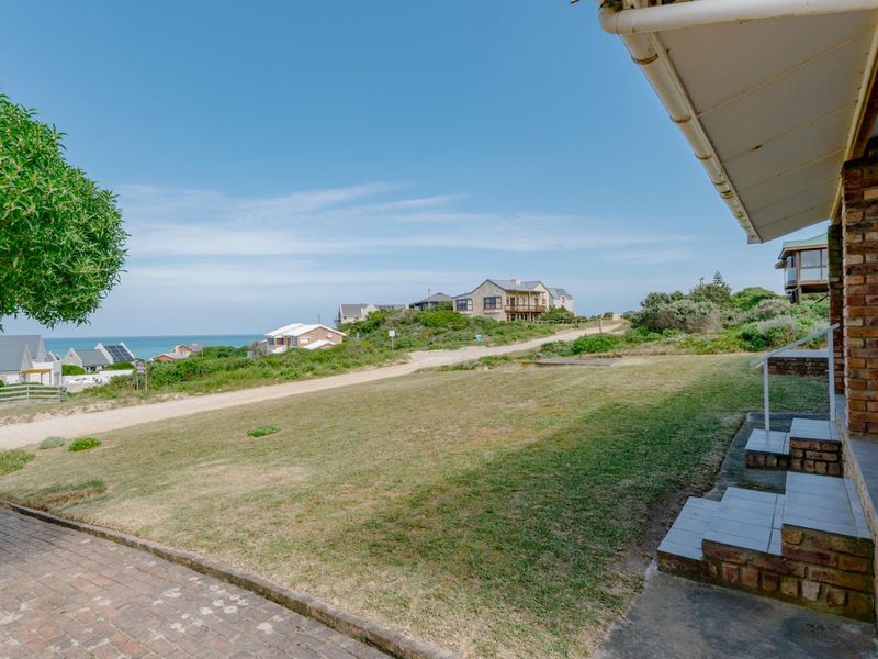 A view of the rear garden and lawn area, featuring brick paving, tiled steps, and a clear outlook towards the coastal landscape.