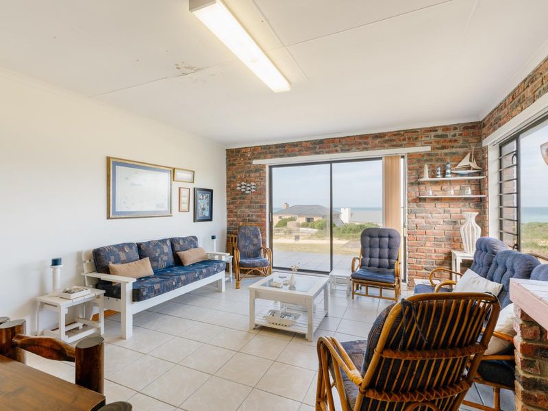 Living room featuring an exposed brick wall, ceramic floor tiles, and large sliding glass doors providing natural light and coastal views.