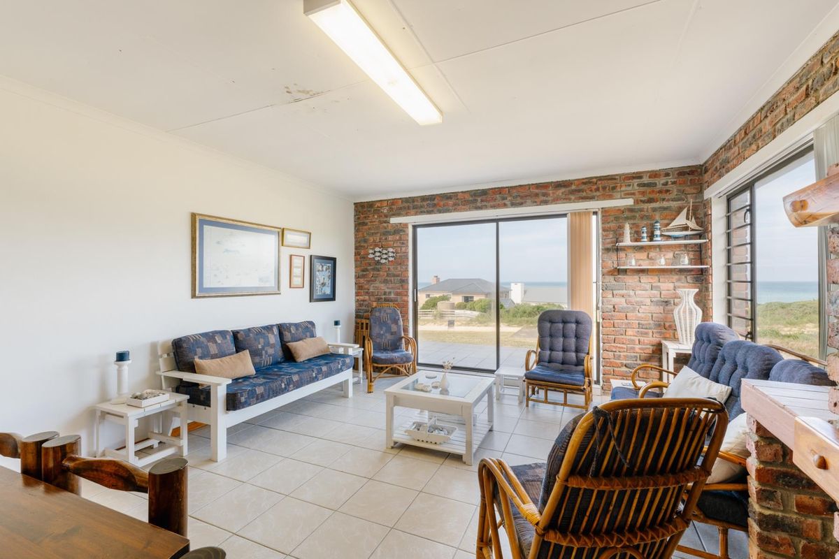 Living room featuring an exposed brick wall, ceramic floor tiles, and large sliding glass doors providing natural light and coastal views.