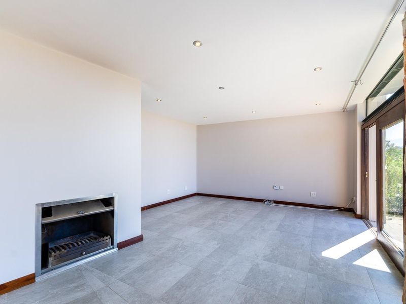 Spacious living area featuring large format floor tiles, a built-in fireplace, recessed lighting, and sliding glass doors opening to an outdoor space.