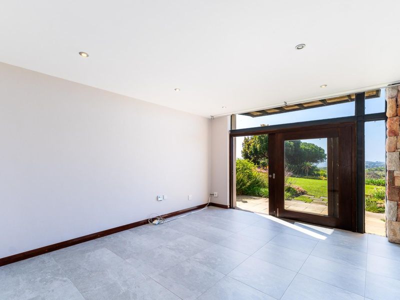 Bright and spacious living area featuring large sliding glass doors, modern tiled flooring, and a distinctive stone-clad feature wall with garden access.